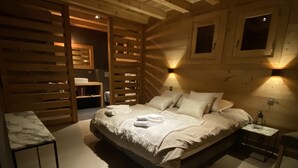 Um quarto aconchegante com uma cama grande, paredes de madeira e iluminação embutida.