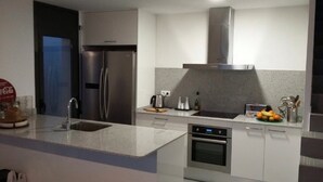 Une cuisine moderne dotée d’appareils électroménagers en acier inoxydable, d’un four encastré et d’un plan de travail en granit.