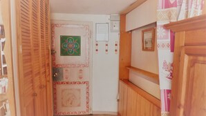 Un corridoio stretto con porte in legno, un termosifone e una parete con un quadro incorniciato.