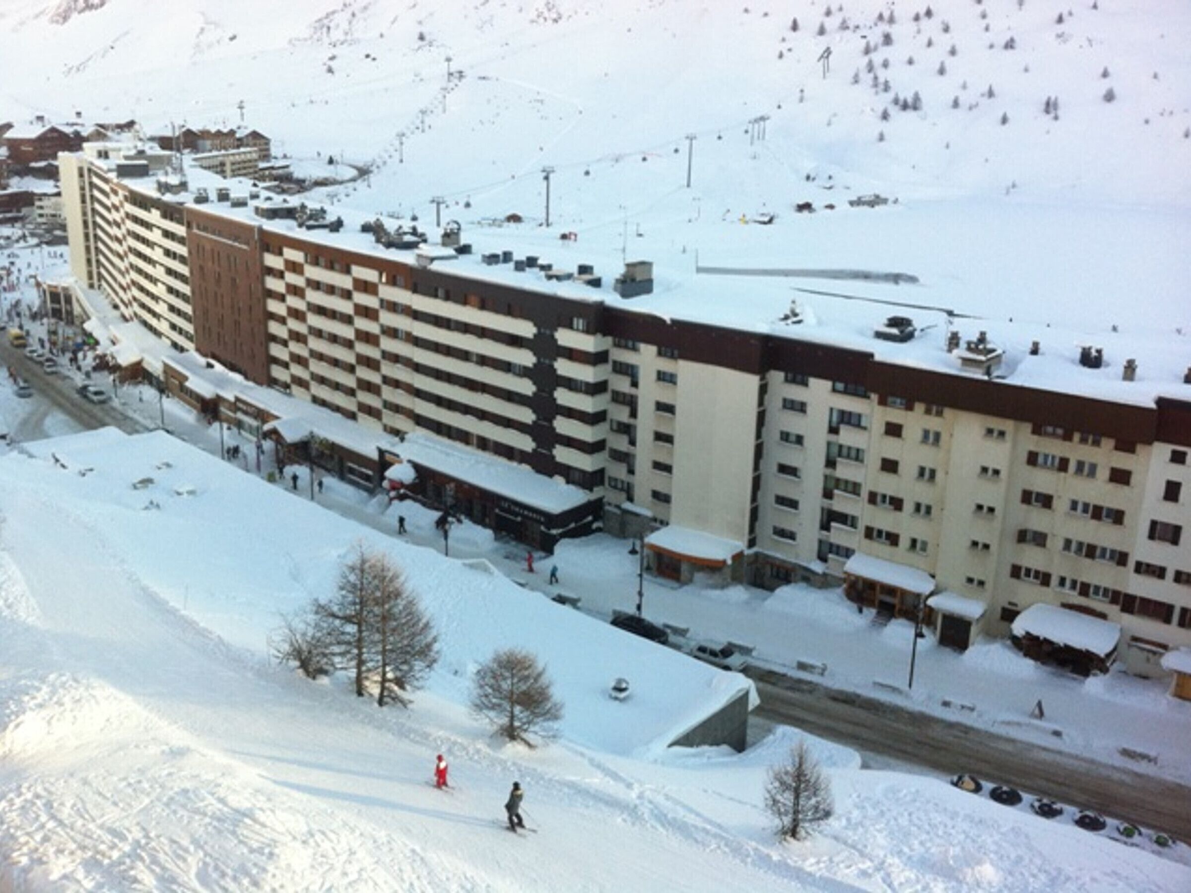 A multi-story hotel with a snow-covered roof and adjacent ski slopes.