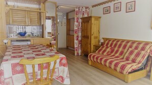 Una stanza accogliente con un tavolo da pranzo in legno, un divano a righe e un angolo cottura con mobili in legno e una ciotola blu.