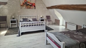 A bedroom with a sloped ceiling, a bed, a chair, a nightstand, and a painting on the wall. - Gîte near Chambord - 6/7 people (Maslives)