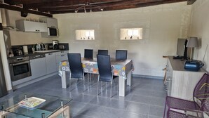A modern kitchen with a dining area, featuring a glass-top table, chairs, and a built-in oven. - Gîte near Chambord - 6/7 people (Maslives)