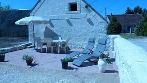 A stone building with a sloped roof, outdoor seating with chairs and a table, and potted plants. - Gîte near Chambord - 6/7 people (Maslives)