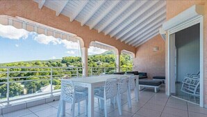 A balcony with a table and chairs, a view of greenery, and a tiled floor. - VILLA BETWEEN SEA AND MOUNTAIN  (Pointe noire)