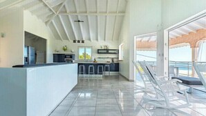 A spacious kitchen with a high ceiling, a bar area, and a view of the outdoors. - VILLA BETWEEN SEA AND MOUNTAIN  (Pointe noire)