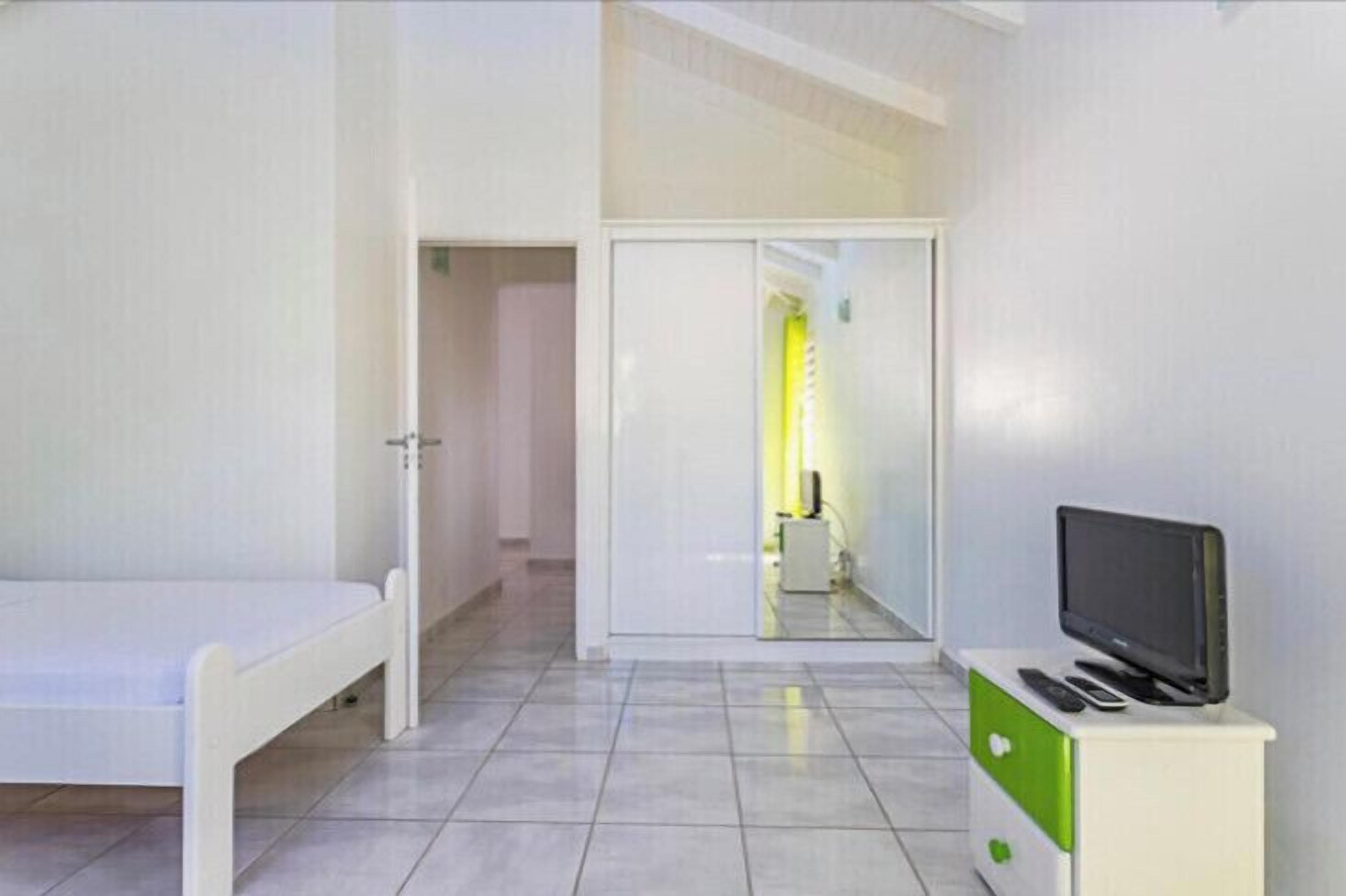 Une chambre d’hôtel avec un lit, un téléviseur posé sur un meuble et une porte donnant accès à une salle de bain.