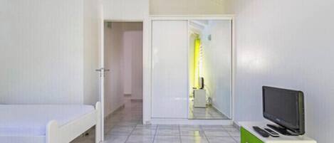 Une chambre d’hôtel avec un lit, un téléviseur posé sur un meuble et une porte donnant accès à une salle de bain.