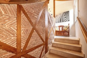 A staircase with a wooden frame and brick wall, leading to a room with a zebra-patterned wall and a wooden cabinet.