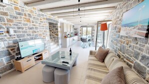 Un salon moderne avec des murs en pierre, une table basse en verre et un canapé.