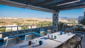 Une terrasse extérieure avec une table et des chaises, une piscine et une vue sur le paysage.