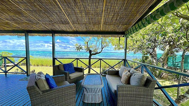 Un espacio de estar techado al aire libre con muebles de mimbre y vista al océano.