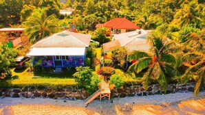 A beachfront property with multiple houses, a wooden staircase, and lush greenery.