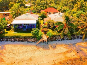 A beachfront property with multiple houses, a wooden staircase, and lush greenery.