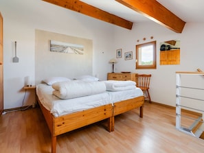 Quarto com cama de madeira, escrivaninha, cadeira e guarda-roupa.
