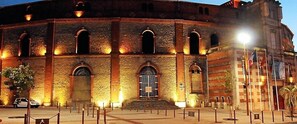 Un bâtiment historique doté d’une entrée centrale en arc de cercle, de nombreuses fenêtres et d’une façade en briques.