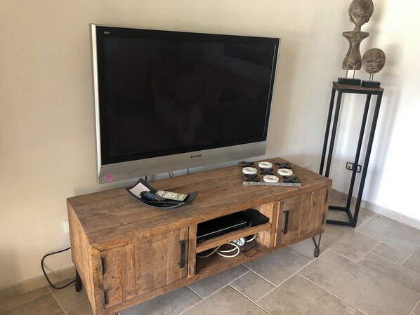A wooden entertainment center with a flat-screen TV, a remote control holder, and decorative items.