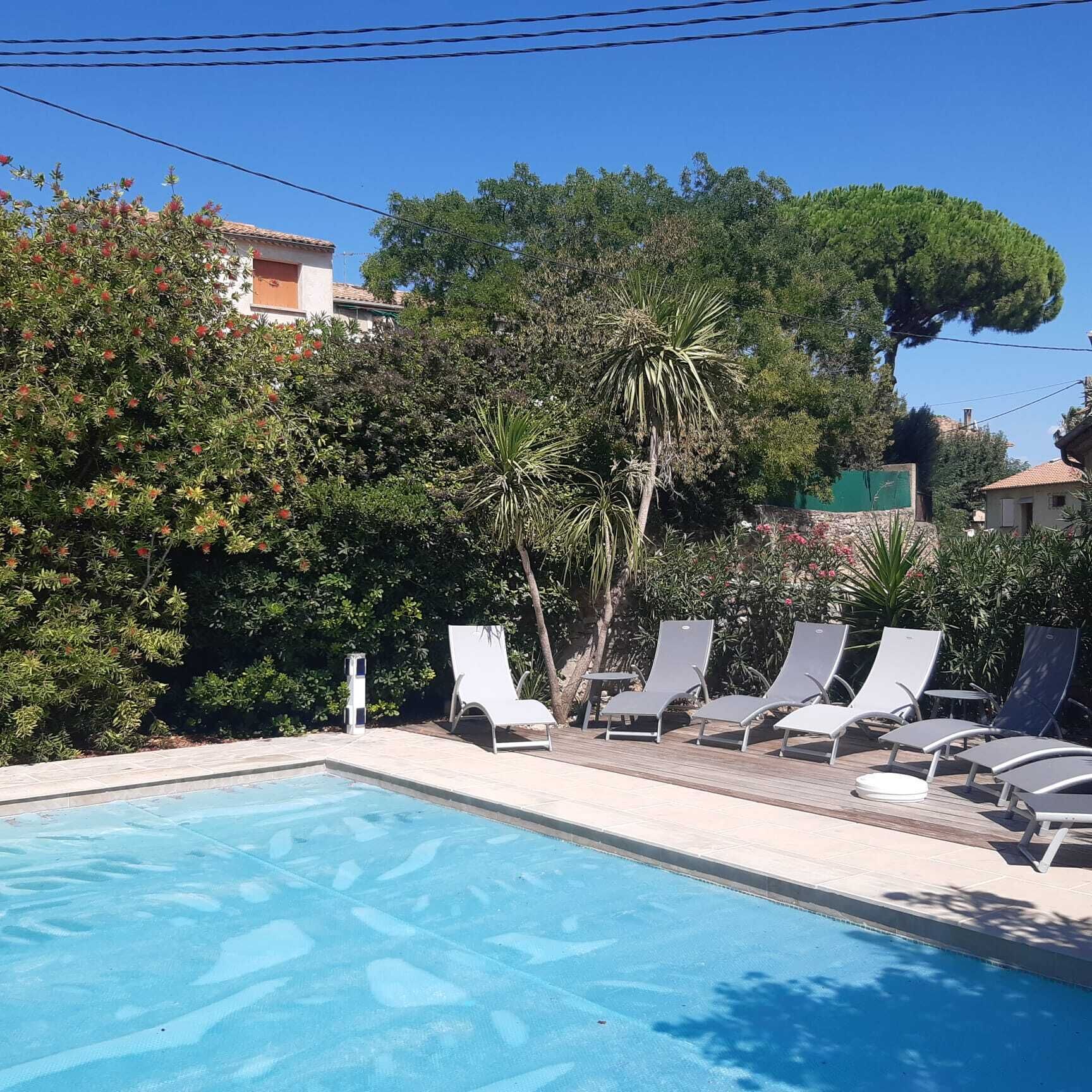 A swimming pool with lounge chairs and a stone wall.