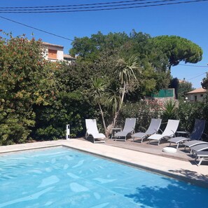 Une piscine avec des chaises longues et un mur en pierre.