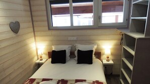 Een slaapkamer met een bed, twee bedlampen, een raam en een houten wand.