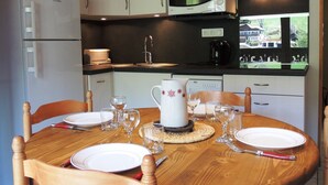 Een keuken met witte kasten, een magnetron, een koffiezetapparaat en een eettafel gedekt met borden, glazen en bestek.