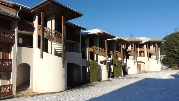 Een rij chalets met houten balkons en een sneeuwbedekte grond.