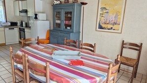 A dining area with a round table, chairs, a cabinet, and a painting on the wall. - KREISKER 2 - Maison Jumelée, Jardin - CA6008 (Carnac)
