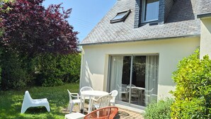 A house with a patio, a dining table with chairs, a white chair, and a red chair. - KREISKER 2 - Maison Jumelée, Jardin - CA6008 (Carnac)
