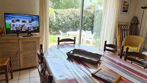A dining area with a table, chairs, a television, and a view of the outdoors. - KREISKER 2 - Maison Jumelée, Jardin - CA6008 (Carnac)