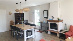Un ampio soggiorno con un tavolo da pranzo in legno, sedie nere, un camino e una grande finestra.