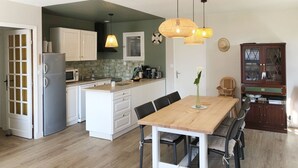 Una cucina moderna con mobili bianchi, forno a incasso e zona pranzo con tavolo e sedie in legno.