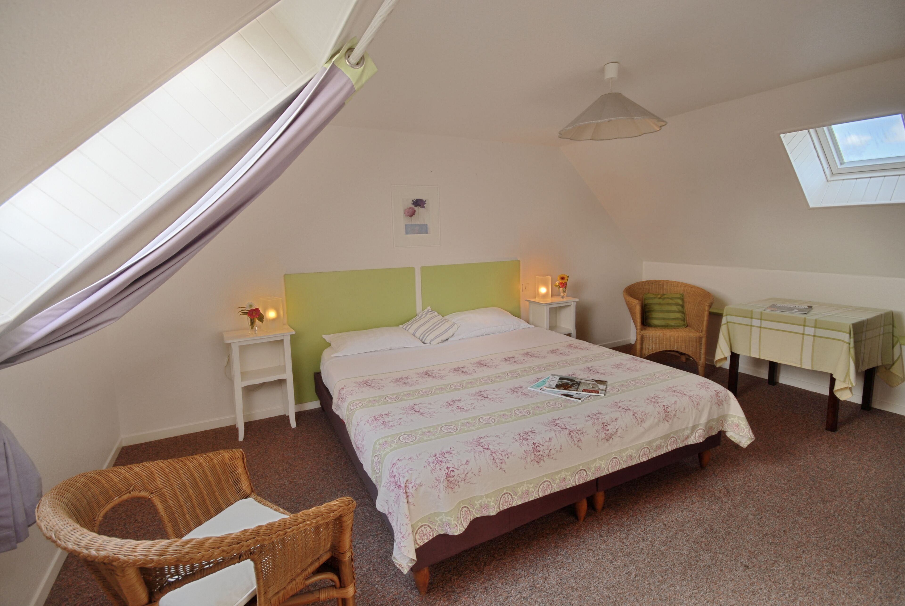 Une chambre à coucher avec un lit, une chaise, une petite table et une fenêtre.