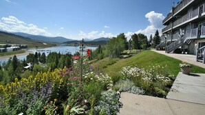 Een hotel met uitzicht op een meer, bergen en een tuin met diverse bloemen.