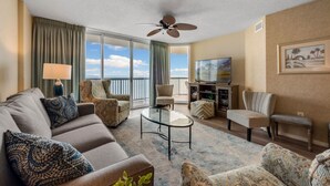 A hotel room with a balcony, a ceiling fan, a TV, and a sofa. - 12th Floor AshWorth, Oceanfront, Wifi, Private Balcony | AshWorth - 1202 (North Myrtle Beach)