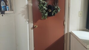 A closed door with a brown panel, a doorknob, and a small shelf with cleaning supplies. - Cozy Escape close to Yellowstone & Grand Teton NP, BYUI, River Beach sleeps 9 (St Anthony)