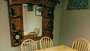 A dining area with a wooden table and six chairs, a large mirror with shelves, and a clock. - Cozy Escape close to Yellowstone & Grand Teton NP, BYUI, River Beach sleeps 9 (St Anthony)