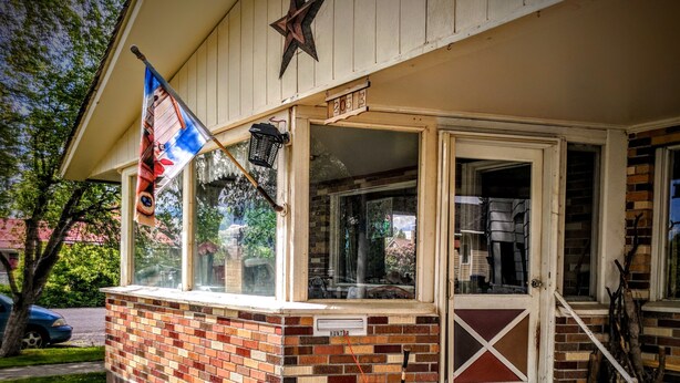 A house with a brick exterior, a porch, and a flag. - Cozy Escape close to Yellowstone & Grand Teton NP, BYUI, River Beach sleeps 9 (St Anthony)