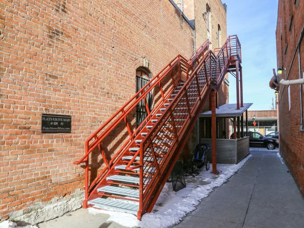 A brick building with a red fire escape and a sign indicating 'Flats Above Main'.