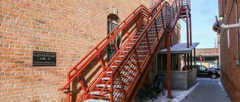 A brick building with a red fire escape and a sign indicating 'Flats Above Main'.