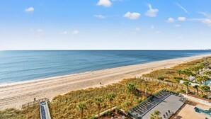 Une vue sur la plage, avec un espace de stationnement et un bâtiment doté d’une piscine.