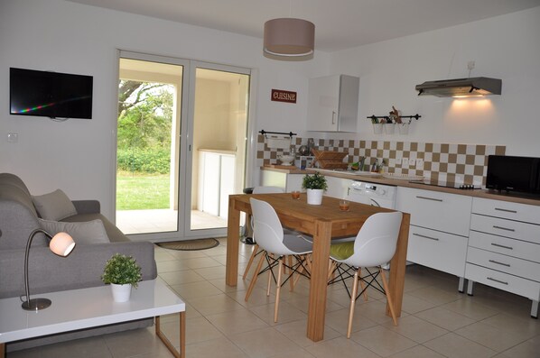 A modern kitchen with a dining table, chairs, and a TV mounted on the wall.