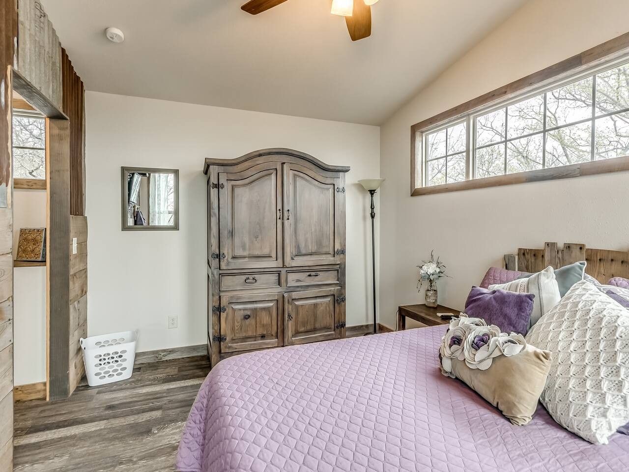 A bedroom with a large bed, wooden wardrobe, and a window with a view.