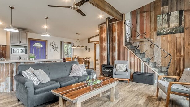 Un vaste espace de vie comprenant un canapé, une table basse et un escalier doté d’une rampe en métal.
