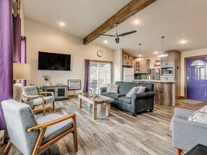 A modern living room with a sofa, armchairs, a coffee table, and a television.