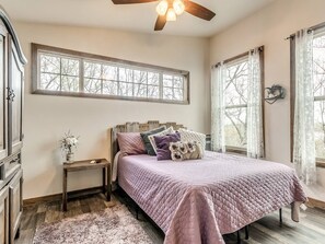 A bedroom with a bed, a nightstand, a dresser, and a window with curtains.