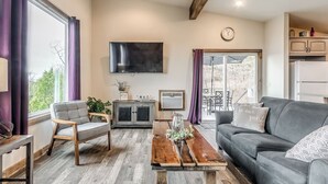 Un salon moderne avec un canapé gris, une table basse en bois et un téléviseur fixé au mur.