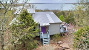 Une cabane avec un toit en métal, une porte violette et un escalier menant à une terrasse.