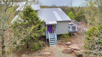 Une cabane avec un toit en métal, une porte violette et un escalier menant à une terrasse.