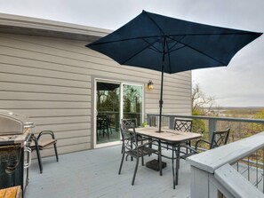 A covered outdoor patio with a table and chairs, a grill, and a large umbrella.