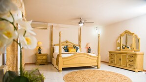 A bedroom with a four-poster bed, a round rug, a vanity with a mirror, and a ceiling fan. - Beautiful Gated Community Vacation Home, Close to all Tourist Attractions (St. Anne's Bay)